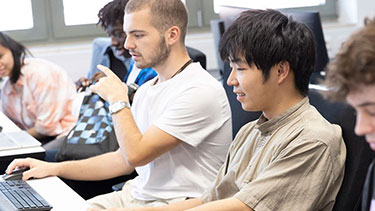 Students working on a row of laptops in classroom