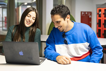 Male and female students learning on campus with laptop