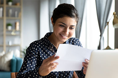 Female reading letter while sat infront of laptop