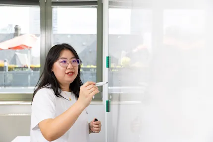 Faculty members writing on a glass board in a classroom.