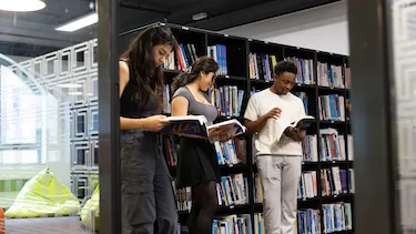 Students holding and reading books in library
