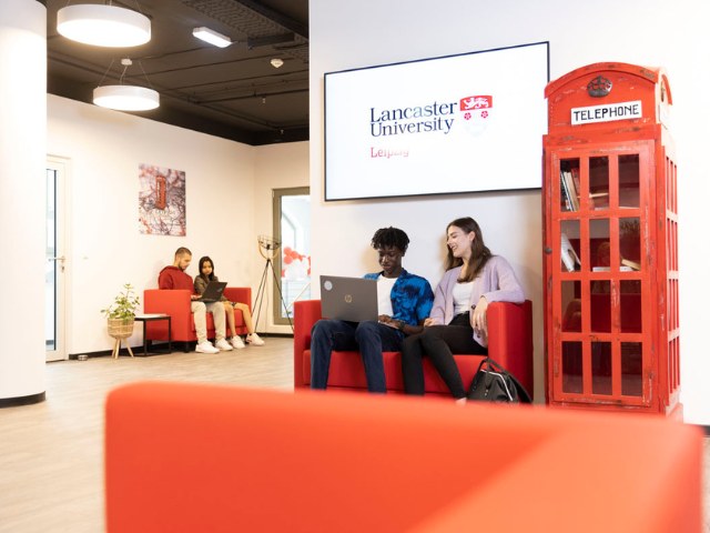 Two Lancaster Leipzig students sat on a sofa next too a British red telephone booth.